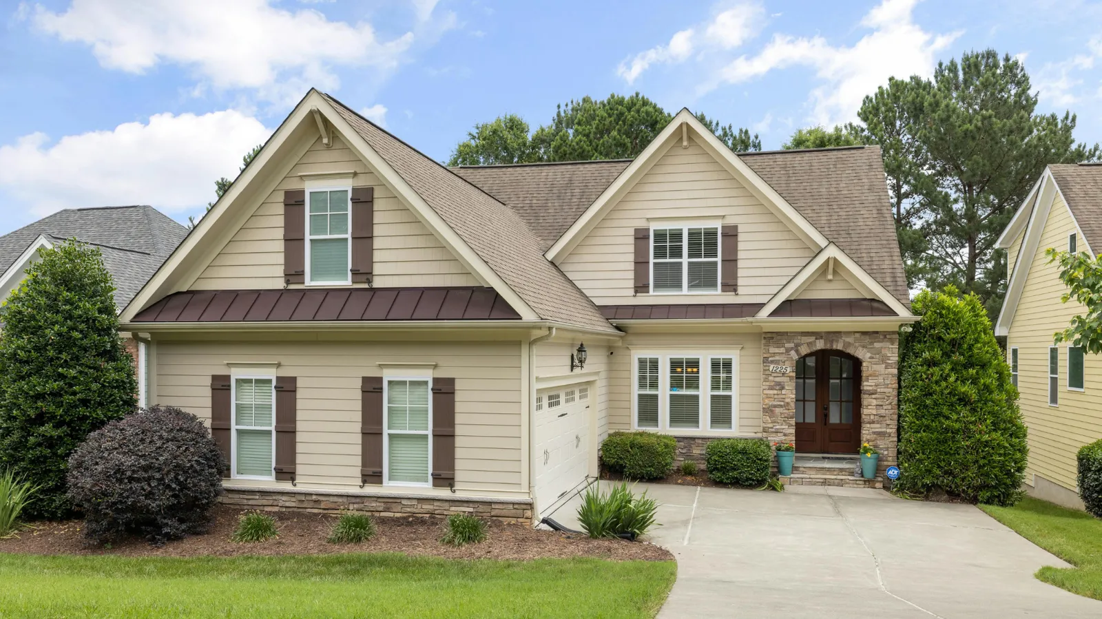 Brown shingle roof and stone arched entryway on a tan home
